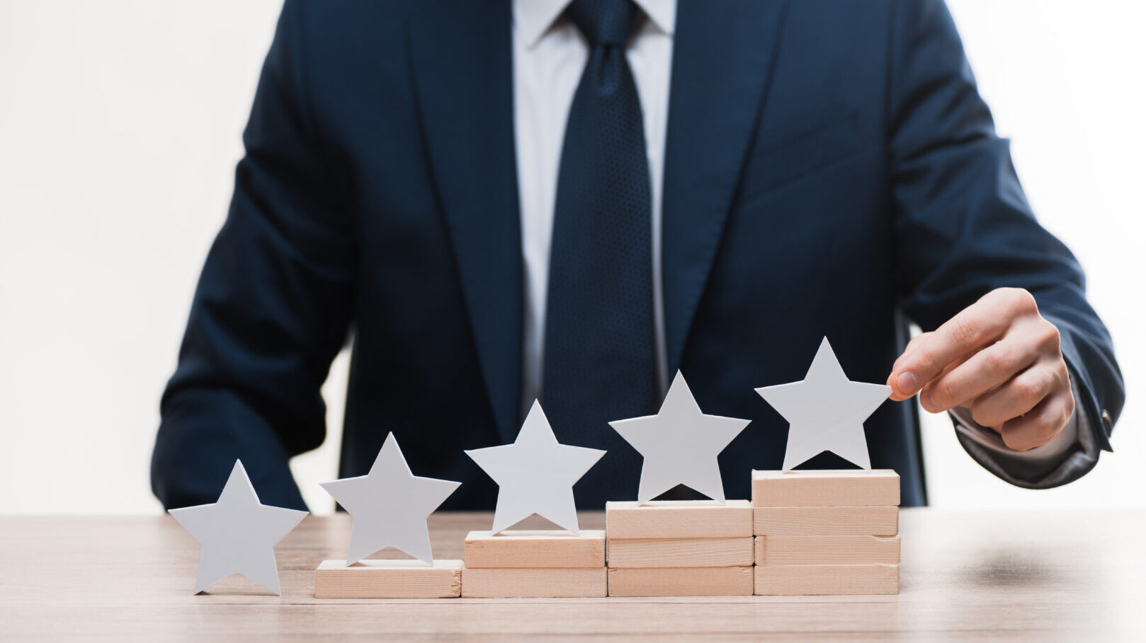 Business professional in a suit arranging star ratings on a desk, with RepMove logo, indicating high performance and quality in field sales.